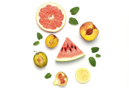 Tropical Summer Fruit Concept. Creative layout made of fresh ripe watermelon, peach, plum, fig, lemon, grapefruit and mint leaves on white background. Flat lay, top view, copy space. Food background.の写真素材