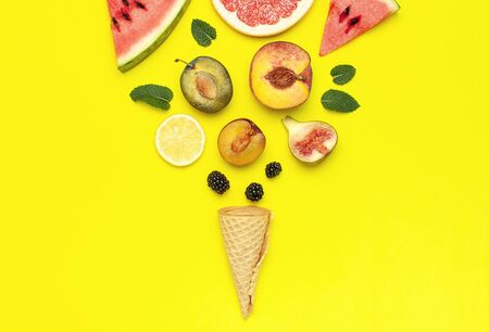 Tropical Summer Fruit Concept. Creative layout made of fresh ripe watermelon, peach, plum, fig, lemon, grapefruit, waffle ice cream cup, mint leaves on yellow background. Flat lay top view copy space.の写真素材