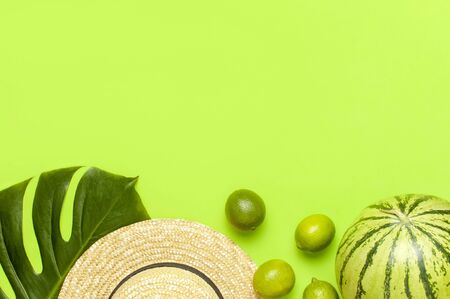 Ripe watermelon berry, summer straw hat, whole limes, tropical leaf monstera on green backgroundの写真素材