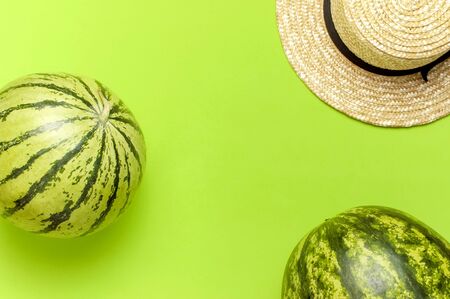 Ripe watermelon berry, summer straw hat on green backgroundの写真素材