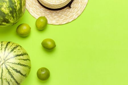 Ripe watermelon berry, summer straw hat, whole limes, tropical leaf monstera on green backgroundの写真素材