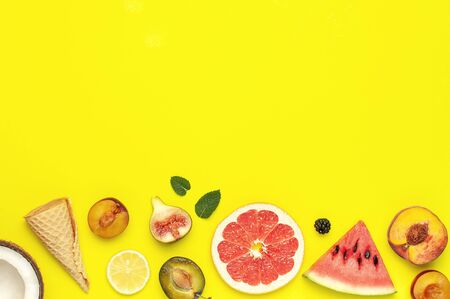 Tropical Summer Fruit Concept. Creative layout made of fresh ripe watermelon, peach, plum, fig, lemon, grapefruit, waffle ice cream cup, mint leaves on yellow background. Flat lay top view copy space.の写真素材