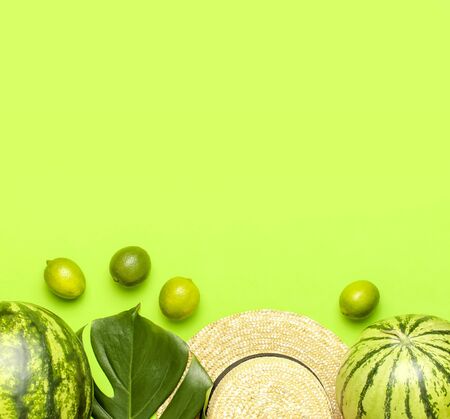 Ripe watermelon berry, summer straw hat, whole limes, tropical leaf monstera on green backgroundの写真素材