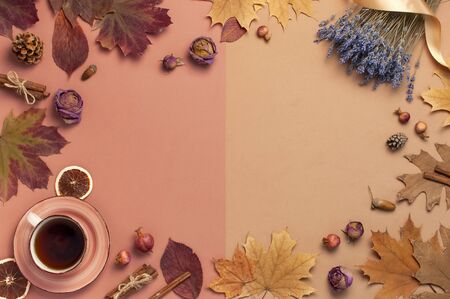 Autumn Flat lay composition. Cup of tea, autumn dry leaves, roses flowers, lavender, orange circle cones decorative pomegranate cinnamon sticks on brown pink backgroundの写真素材