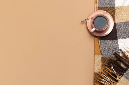 Autumn Flat lay composition. Cup of tea, checkered cozy plaid, lavender on brown beige backgroundの写真素材