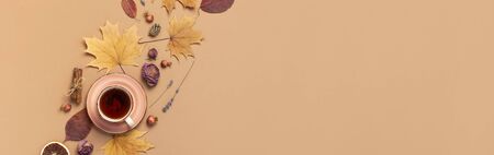 Autumn Flat lay composition. Cup of tea, autumn dry bright leaves, roses flowers, orange circle, cones, decorative pomegranate, cinnamon sticks on brown beige backgroundの写真素材