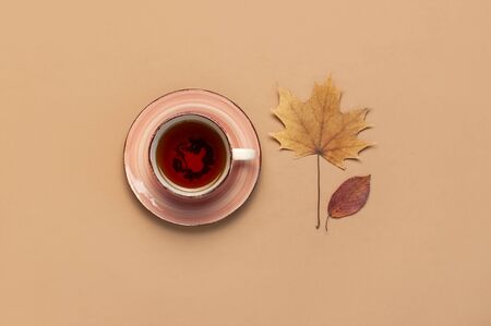 Autumn Flat lay composition. Cup of tea, autumn dry bright leaves, roses flowers, orange circle, cones, decorative pomegranate, cinnamon sticks on brown beige backgroundの写真素材