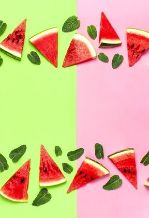 Watermelon pattern. Juicy slices of ripe red watermelon and mint leaves on multicolored pink and green background. Flat lay, top view, copy space.の写真素材