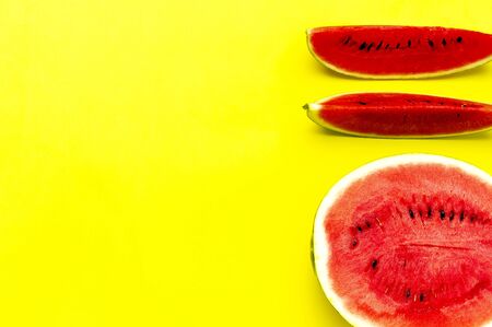 Half and pieces of ripe juicy red watermelon on bright yellow background. Flat lay, top view, copy space.の写真素材