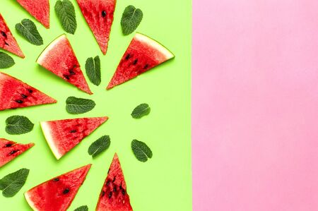 Watermelon pattern. Juicy slices of ripe red watermelon and mint leaves on multicolored pink and green background. Flat lay, top view, copy space.の写真素材