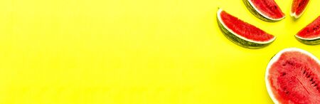 Half and pieces of ripe juicy red watermelon on bright yellow background. Flat lay, top view, copy space.の写真素材