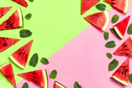 Watermelon pattern. Juicy slices of ripe red watermelon and mint leaves on multicolored pink and green background. Flat lay, top view, copy space.の写真素材