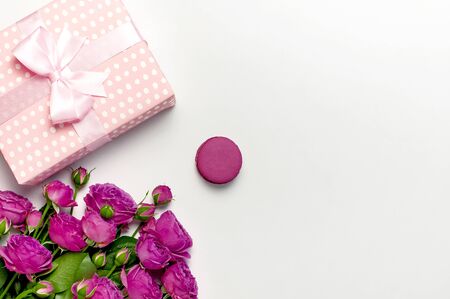 Gift box with ribbon, bright pink roses, cake macaron or macaroon on light gray background. Flat lay, top view, copy space.の写真素材