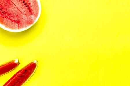 Half and pieces of ripe juicy red watermelon on bright yellow background. Flat lay, top view, copy space.の写真素材