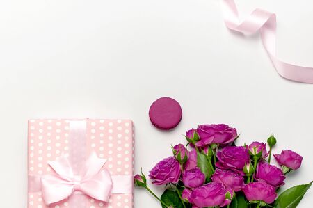 Gift box with ribbon, bright pink roses, cake macaron or macaroon on light gray background.の写真素材
