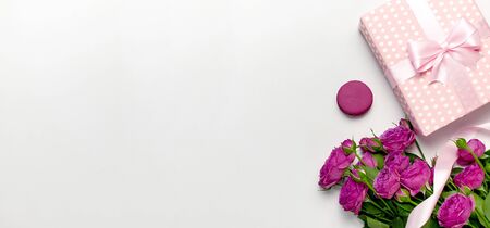 Gift box with ribbon, bright pink roses, cake macaron or macaroon on light gray background.の写真素材