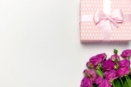Gift box with delicate ribbon and bouquet of bright pink roses on light gray background. Flat lay, top view, copy space.の写真素材