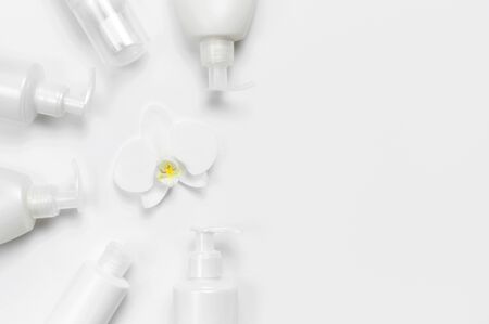 White cosmetic bottle containers and orchid flower on white background top view flat lay.の写真素材
