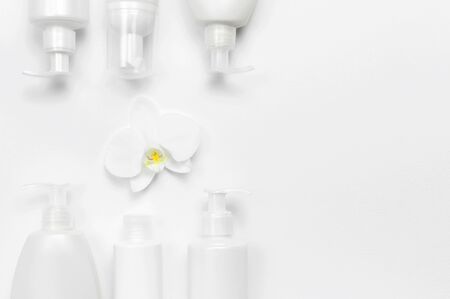 White cosmetic bottle containers and orchid flower on white background top view flat lay.の写真素材