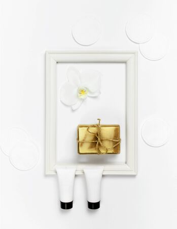 White cosmetic bottle containers, natural soap, orchid flower on white background top view flat lay. Cosmetics SPA branding mock-up.の写真素材