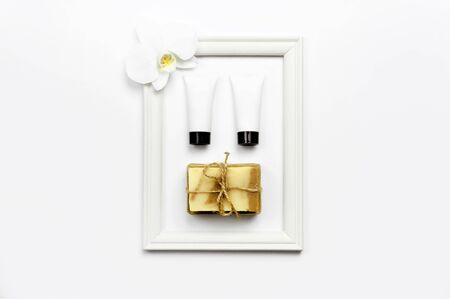 White cosmetic bottle containers, natural soap, orchid flower on white background top view flat lay. Cosmetics SPA branding mock-up.の写真素材
