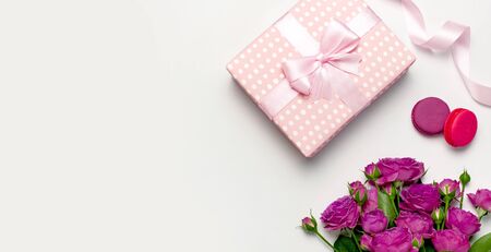 Gift box with ribbon, bright pink roses, cake macaron or macaroon on light gray background. Flat lay, top view, copy space.の写真素材