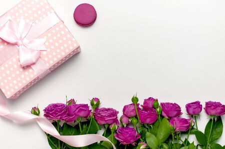 Gift box with ribbon, bright pink roses, cake macaron or macaroon on light gray background. Flat lay, top view, copy space.の写真素材