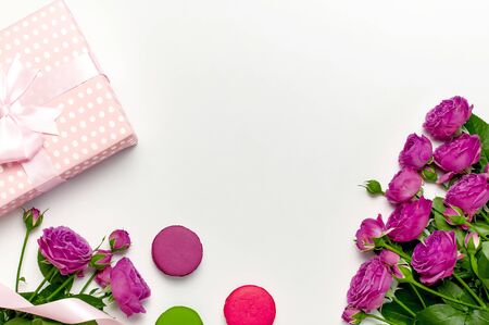 Gift box with ribbon, bright pink roses, cake macaron or macaroon on light gray background. Flat lay, top view, copy space.composition.の写真素材