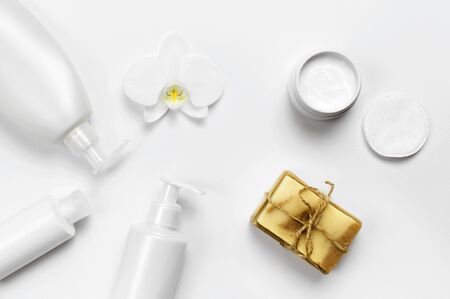 White cosmetic bottle containers, natural soap, orchid flower on white background top view flat lay. Cosmetics SPA branding mock-up.の写真素材