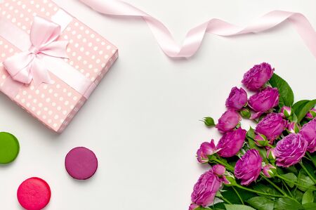 Gift box with ribbon, bright pink roses, cake macaron or macaroon on light gray background.の写真素材