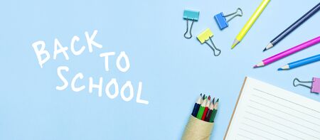 Back to school concept. Wooden colored pencils, clean school notebook in line, paper clips on blue background top view flat lay copy space. Pencils for drawing, objects for creativity.の写真素材