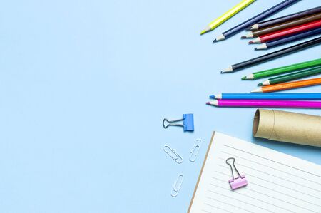 Back to school concept. Wooden colored pencils, clean school notebook in line, paper clips on blue background top view flat lay copy space. Pencils for drawing, objects for creativity.の写真素材