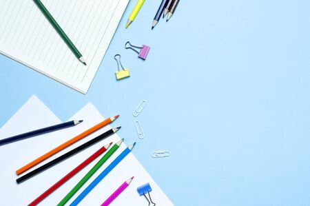 Back to school concept. Wooden colored pencils, clean school notebook in line, paper clips on blue background top view flat lay copy space. Pencils for drawing, objects for creativity.の写真素材