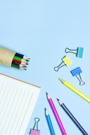Back to school concept. Wooden colored pencils, clean school notebook in line, paper clips on blue background top view flat lay copy space. Pencils for drawing, objects for creativity.の写真素材