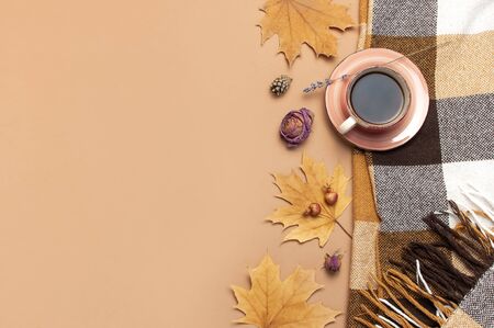 Autumn Flat lay composition. Cup of tea, checkered plaid, autumn dry leaves, roses flowers, orange circle cones decorative pomegranate cinnamon sticks on brown beige background top view. Fall concept.の写真素材