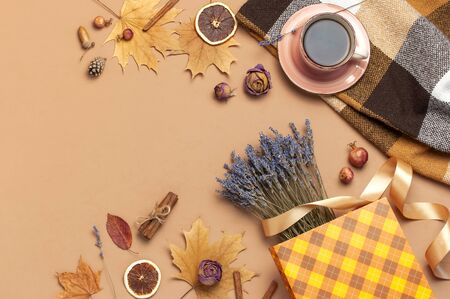 Autumn Flat lay composition. Cup of tea, autumn dry leaves, roses flowers, lavender, gift bag cones decorative pomegranate cinnamon sticks on brown pink background top view. Autumn, fall concept.の写真素材