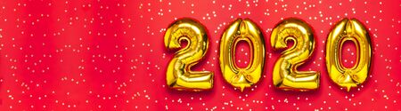 2020 inflatable golden numbers with confetti in the shape of stars on red background. New year winter decoration, holiday symbol. Merry Christmas greeting card. Happy New Year. Flat lay.の写真素材