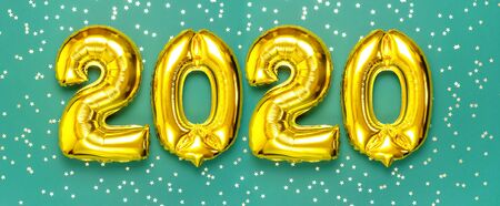 2020 inflatable golden numbers with confetti in the shape of stars on green background. New year winter decoration, holiday symbol, party item. Merry Christmas greeting card. Happy New Year. Flat lay.の写真素材