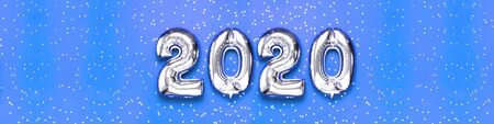2020 inflatable silvery numbers with confetti in the shape of stars on blue background. New year winter decoration, holiday symbol, party item. Merry Christmas greeting card. Happy New Year. Flat lay.の写真素材