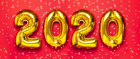 2020 inflatable golden numbers with confetti in the shape of stars on red background. New year winter decoration, holiday symbol. Merry Christmas greeting card. Happy New Year. Flat lay.の写真素材