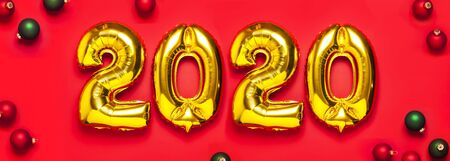 2020 inflatable golden numbers with red and green christmas balls on red background. New year winter decoration, holiday symbol, party item. Merry Christmas greeting card. Happy New Year. Flat lay.の写真素材
