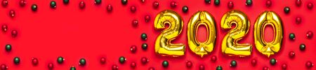 2020 inflatable golden numbers with red and green christmas balls on red background. New year winter decoration, holiday symbol, party item. Merry Christmas greeting card. Happy New Year. Flat lay.の写真素材