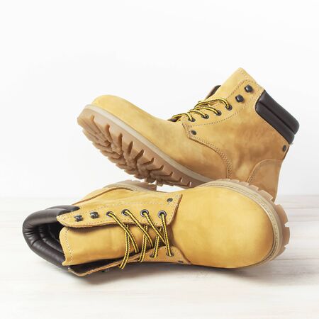 Close-up Yellow men's work boots from natural nubuck leather on wooden white background. Trendy casual footwear youth style. Concept of advertising autumn winter shoes sale shop.の写真素材