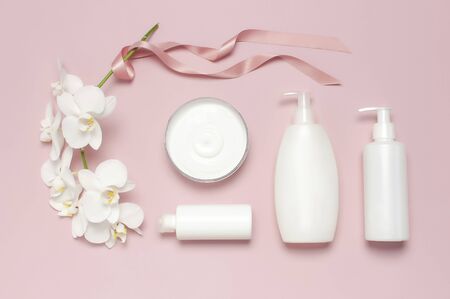 Beauty Spa concept. Opened container with cream, cosmetic bottle containers, white Phalaenopsis orchid flowers on pink background Flat lay top view. Herbal dermatology cosmetic hygienic cream.の写真素材