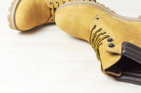 Close-up Yellow mens work boots from natural nubuck leather on wooden white background. Trendy casual footwear youth style. Concept of advertising autumn winter shoes sale shop.の写真素材