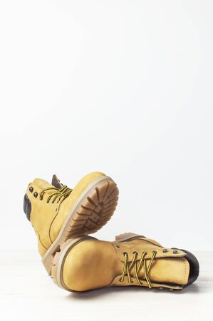 Yellow mens work boots from natural nubuck leather on wooden white background. Trendy casual footwear, youth style. Concept of advertising autumn winter shoes, sale, shop.の写真素材