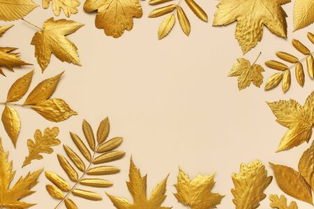 Flat lay creative autumn composition. Frame from Golden leaves on beige background top view copy space. Fall concept. Autumn background. Minimal concept idea, floral design.の写真素材
