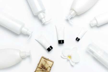 White cosmetic bottle containers, natural soap, orchid flower on white background top view flat lay. Cosmetics SPA branding mock-up. Natural organic beauty product concept. Minimalism cosmetics style.の写真素材