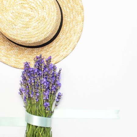 Summer fashion composition. Fresh flowers of purple lavender, women's summer straw hat on light gray background. Flat lay top view copy space. Lavender floral background flower card. Female accessory.の写真素材