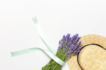 Summer fashion composition. Fresh flowers of purple lavender, women's summer straw hat on light gray background. Flat lay top view copy space. Lavender floral background flower card. Female accessory.の写真素材